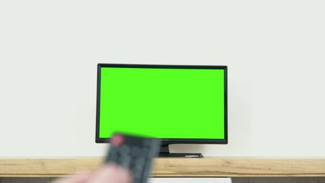 Watching chroma key TV and changing channel by remote control. Channel surfing internet TV green screen