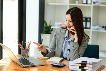 Happy asian business woman have the joy of talking on the smartphone, tablet and laptopon the modern office