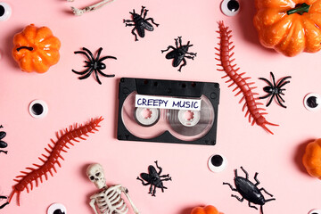 Retro audio cassette with creepy music surrounded by insects, pumpkins and other scary on pink...