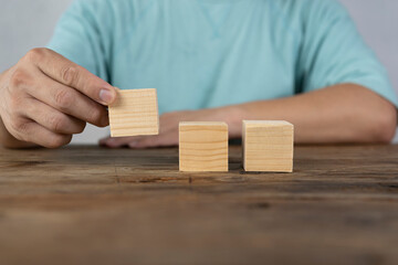 Close-up of three businessmen arranging wooden blocks Wooden toy blocks on a desk can be inserted with image text