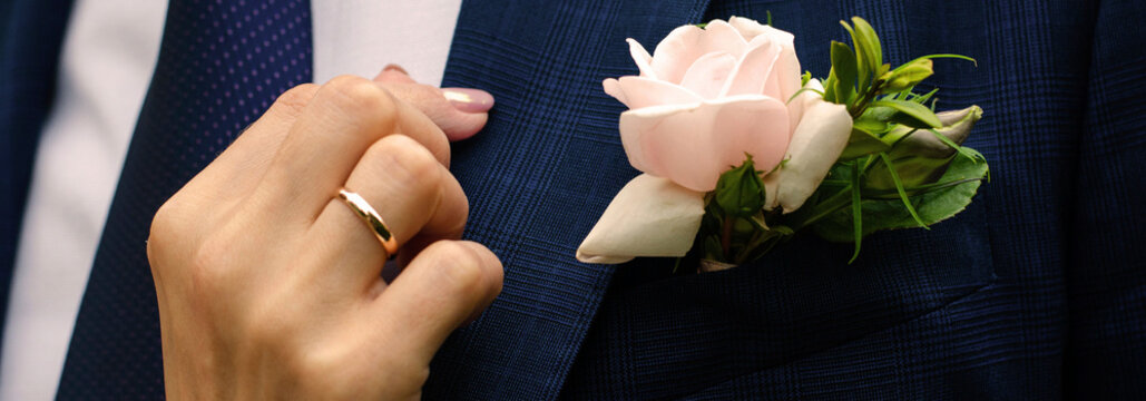 A woman's hand with a ring adjusts her husband's jacket