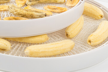 ripe fresh peeled mini bananas in a tray for making dried fruits on a white background