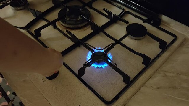Human hand turning on the stove and frying plaice fillet in a pan