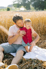 Father and his son have a rest outdoors in a field in summer