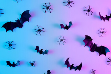 Creative flat lay Halloween background with bats silhouettes and spiders in vibrant gradient...
