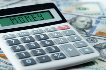 Money text on calculator on us dollars background. Business investment, income, accounting and auditing money concept