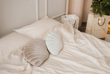 Pillows in the form of seashells lie on a light bed in the bedroom, decorated for Christmas