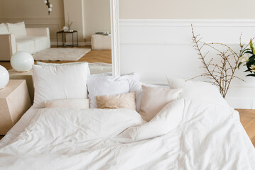 Bright cozy bed with pillows and a mirror. Scandinavian interior of the house