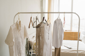 Different clothes on a mobile hanger in a cozy Scandinavian-style bedroom