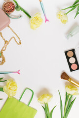 Flat lay, top view table desk frame. Feminine blogger desk workspace with cosmetics, lipstick and tulip flowers on white background.