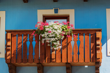 Close-up of a wooden balcony with white and red geranium flowers. Small village of...