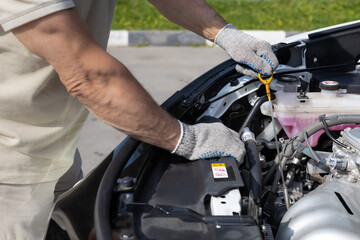 Fototapeta na wymiar a man checks the oil level in a car engine