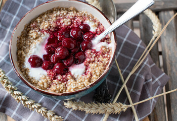 Breakfast cereal porridge with oats, amaranth, quinoa,  yogurt and cooked cherries