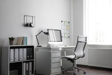 Comfortable white chair near desk in stylish office interior