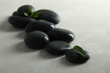 Spa stones with water drops and green leaves on light table