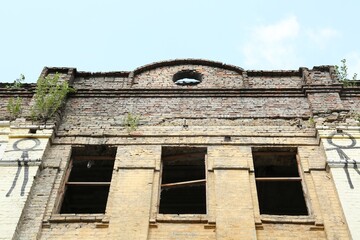 Fototapeta premium Abandoned building with broken windows against blue sky, low angle view