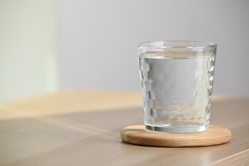 Glass of pure water on wooden table indoors, space for text
