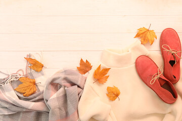 Flat lay composition with sweater and dry leaves on white wooden background, space for text. Autumn season
