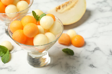 Melon balls and mint on white marble table, closeup. Space for text