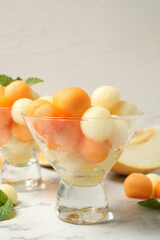 Melon balls and mint on white marble table, closeup