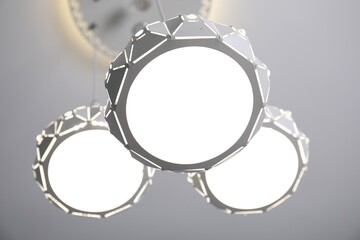 Stylish pendant lamp on white ceiling, low angle view