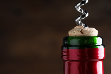 Opening wine bottle with corkscrew on dark brown background, closeup. Space for text