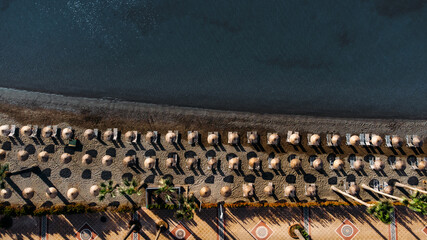 Aerial drone top view to the sand tropical beach with nobody. Row of sunbeds and umbrellas.