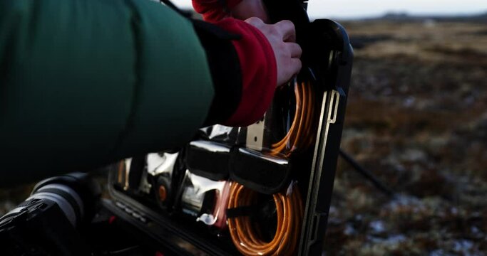 Photographer going through organized flight case with cable pockets, close up hands