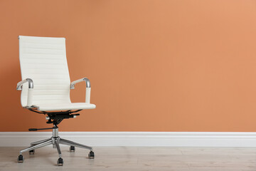 Modern office chair near orange coral wall indoors. Space for text