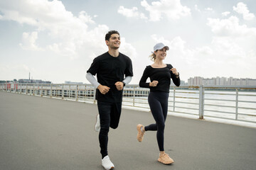 A man and a woman do an active workout, run around the city, use a fitness bracelet - obrazy, fototapety, plakaty