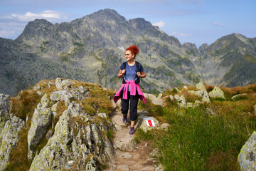 Naklejka na ściany i meble Woman hiker on a trail in the mountains