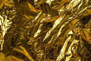 Crumpled foil texture background, close up golden foil