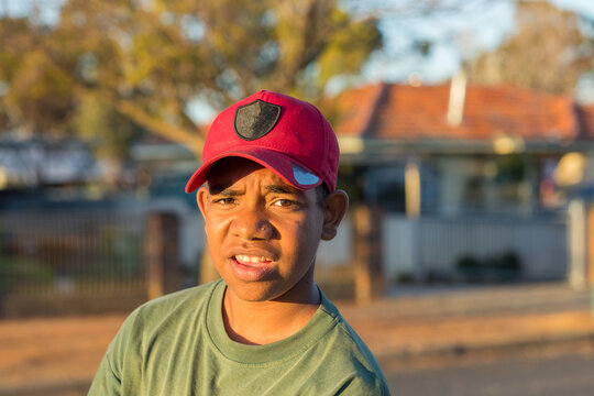 Young aboriginal boy looking at camera outside house