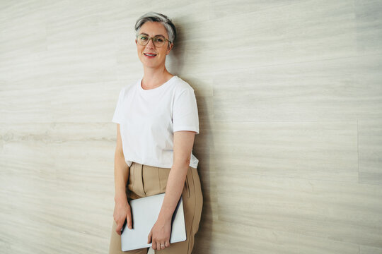 Happy businesswoman standing against a wall in a modern office