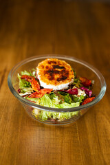 Green salad with cheese on top in a big bowl on a wooden table