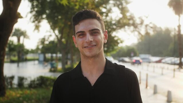 Portrait of mixed race male happy inspired face. Arabic hispanic businessman stands in city on street background of sunset sun.