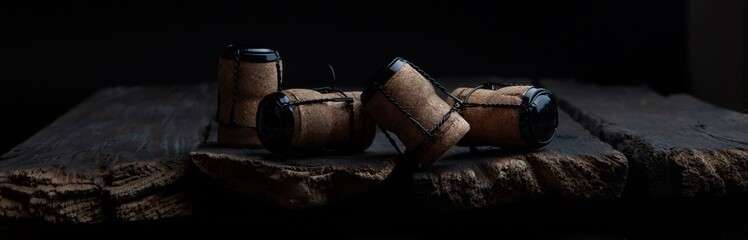 Champagne corks on wooden background. Photo on a dark background. A narrow banner with a place to...