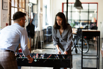 Colleagues having fun at work. Businessman and businesswoman playing table soccer.