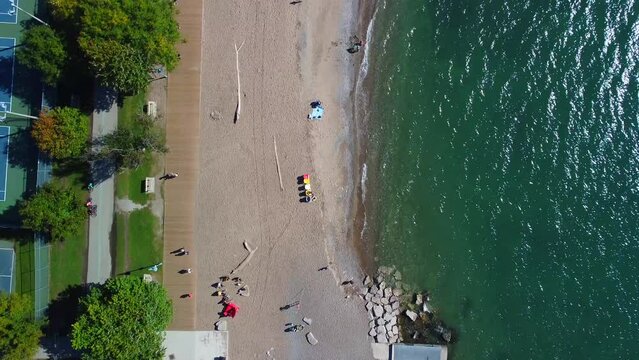 Aerial view of Toronto beaches with drone camera pointed down and flying along the beach.  View of lake, beach and boardwalk.