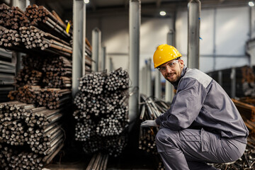 A metallurgy worker is crouching next to iron and metal bars and counting them. Expense of the iron...