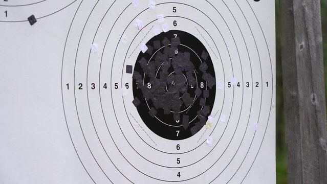 Bullets punching through shooting target close up - Static clip seeing bullet holes penetrating black and white shooting target