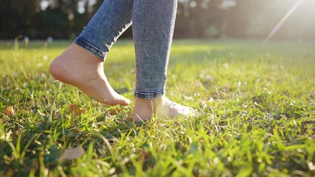 bare feet walking on the grass. a teenager girl takes off her shoes walking bare bare feet on the grass in the park in summer. happy family kid concept. bare feet close-up dream stepping on the grass