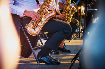 A group of people from a musical brass band who sit on chairs and play music, jazz on golden brass...
