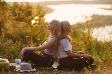 portrait of a smiling senior woman with an adult daughter relaxed outdoors at sunset. copy space. Slow life. Enjoying the little things. spends time in nature in summer