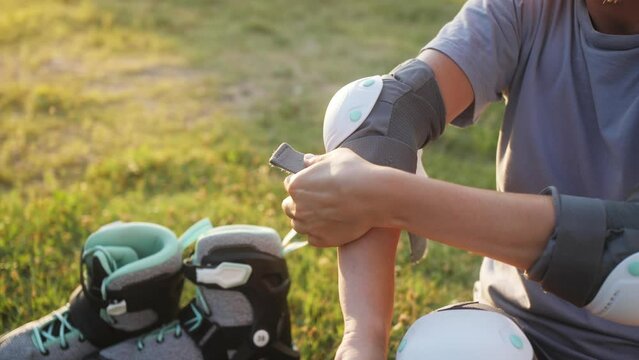 Woman putting on elbow pads before skating roller training. Active outdoor sport.