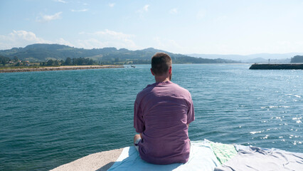 Hombre barbudo blanco sentado en dique de un lago