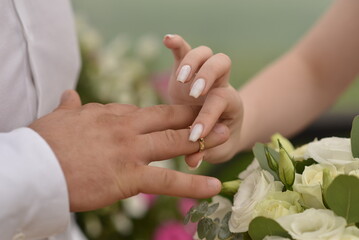 Bride putting on her groom's wedding ring