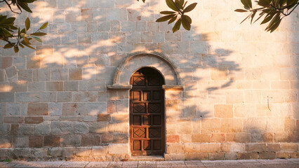Puerta de madera tallada en arco en fachada de piedra 
