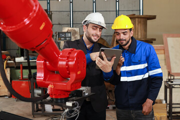 Professional heavy industry technician engineer in safety workwear and businessman maintenance and check part of robot arm machine with tablet in factory automotive. Industrial and technology concept