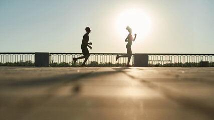Sports couple running on sunny background in city